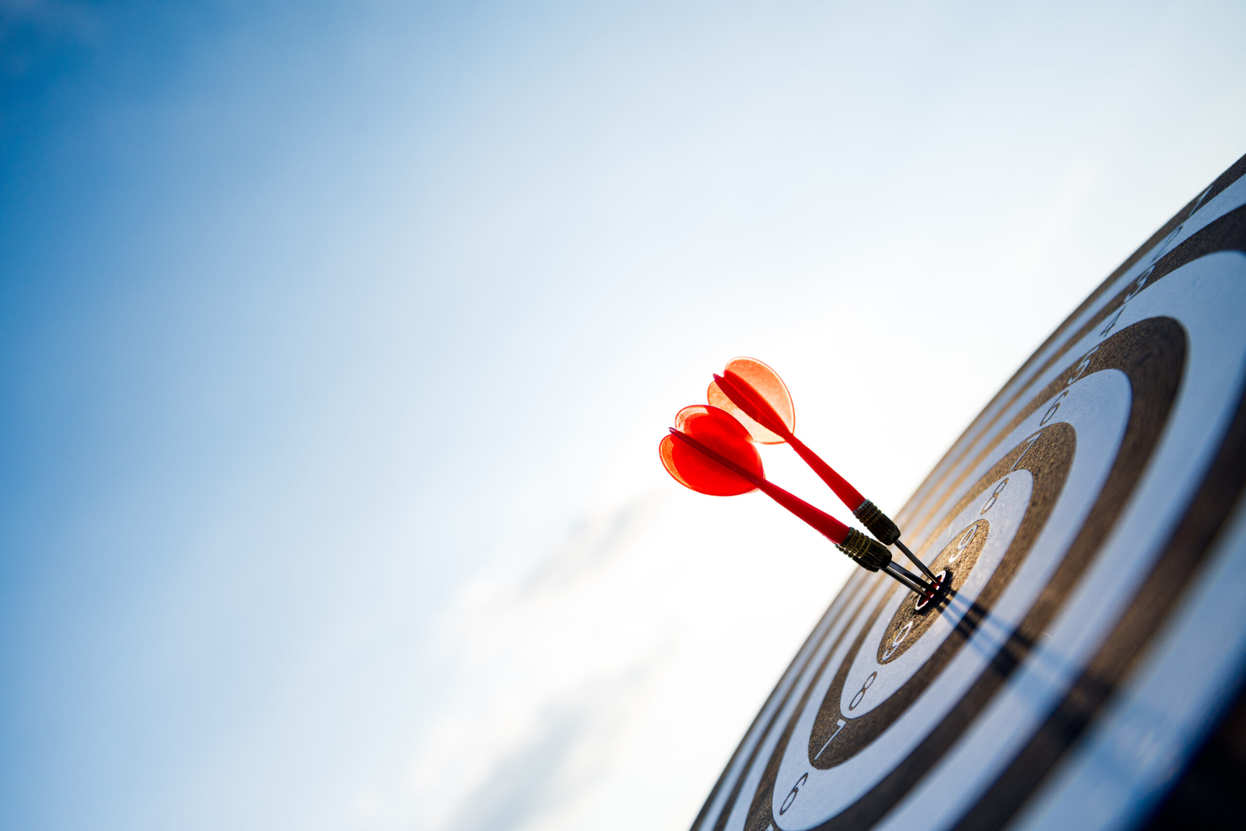 Close up shot red darts arrows in the target center on dark blue sky background. Business target or goal success and winner concept.